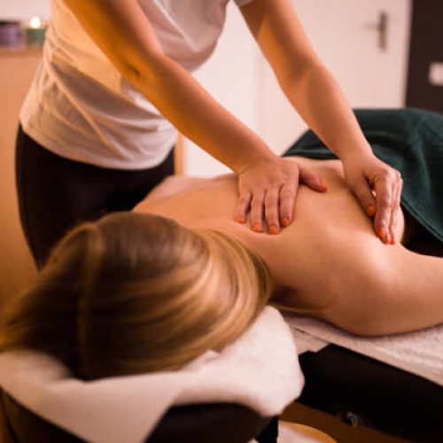 Back massage, young blonde woman enjoying  massage at beauty spa salon